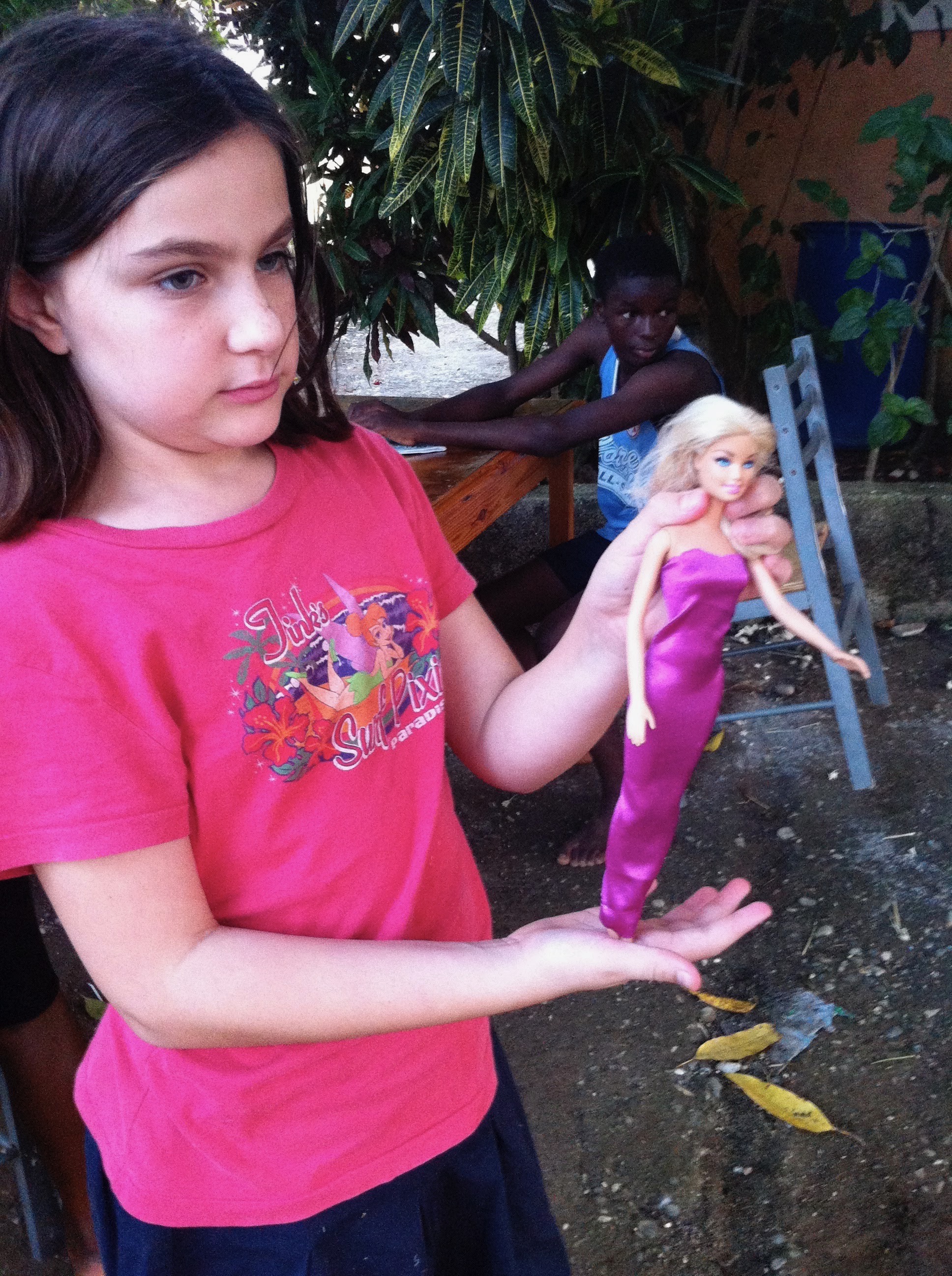 Childhood photograph of Bee Mangine holding a doll dressed in purple.