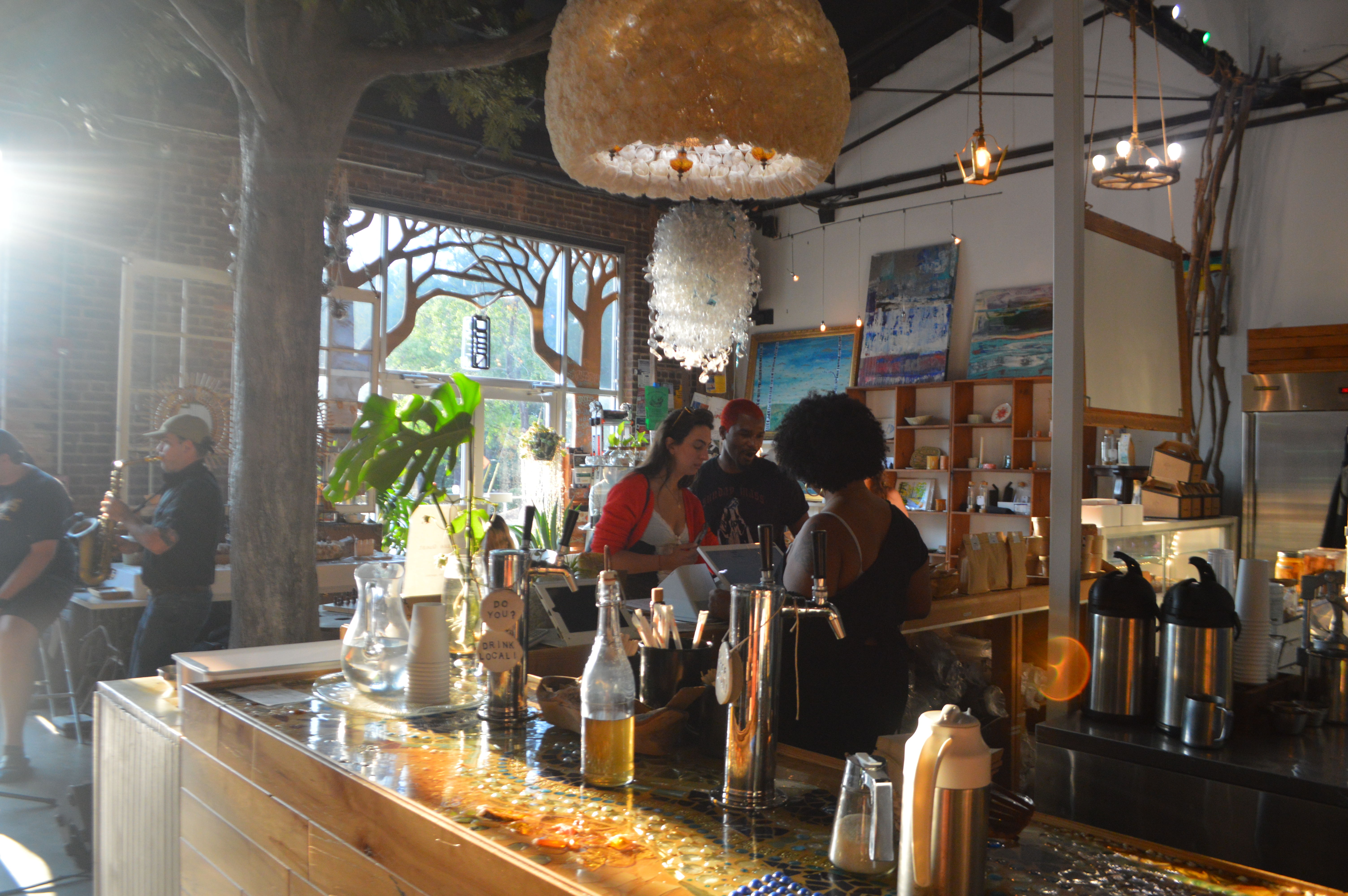 The interior of Lucky Tree filled with customers, artwork and hanging fixtures.