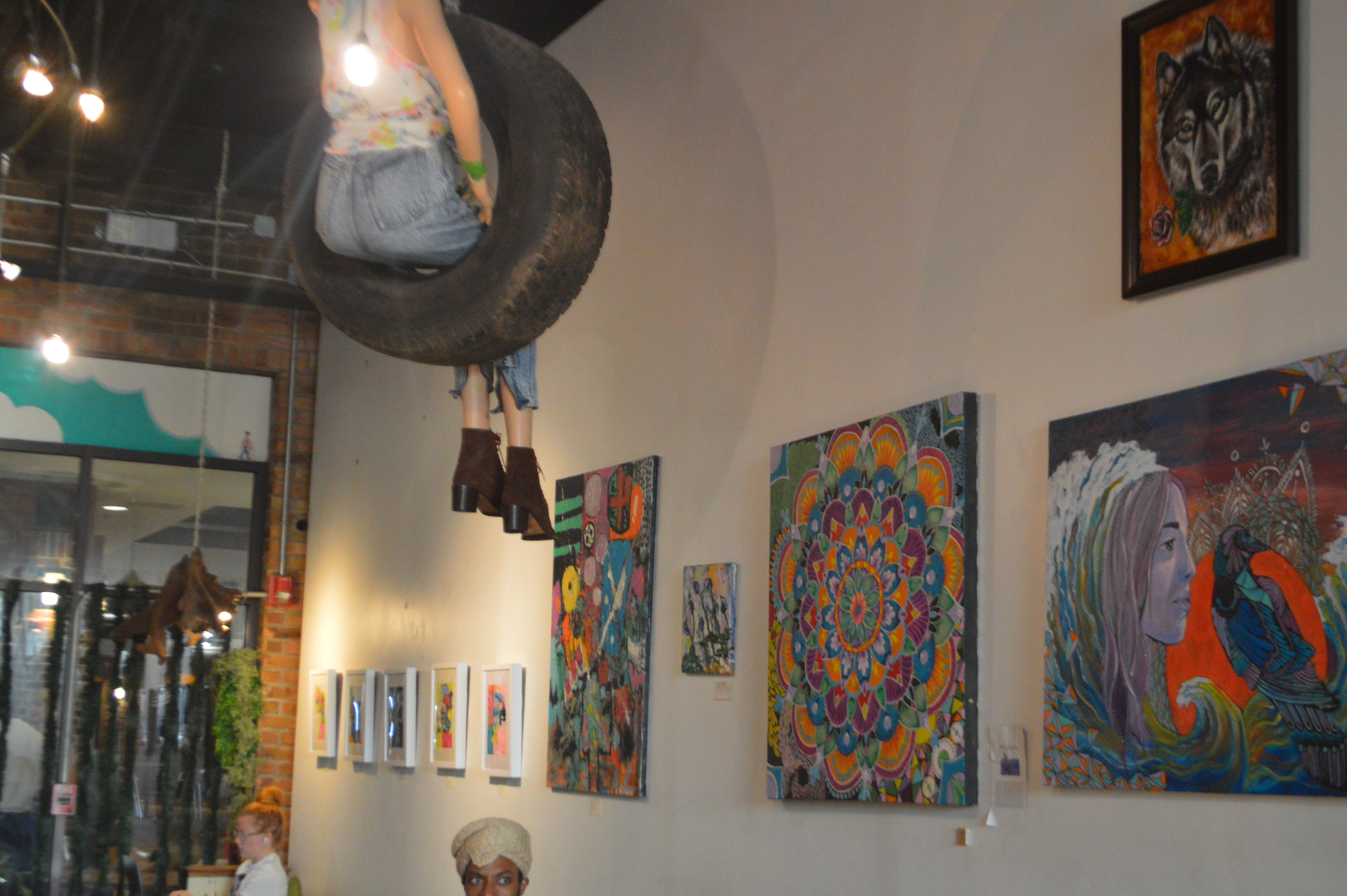 A suspended tire swing surrounded by artwork inside Lucky Tree.